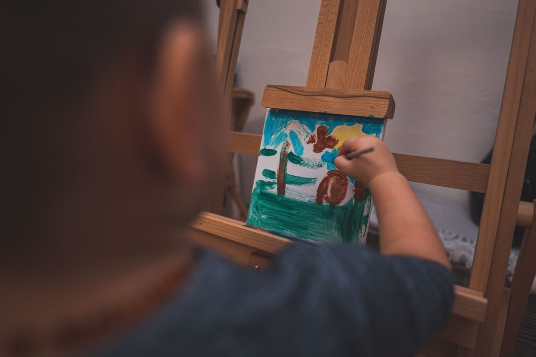 Enfant peignant sur un chevalet pendant un atelier créatif