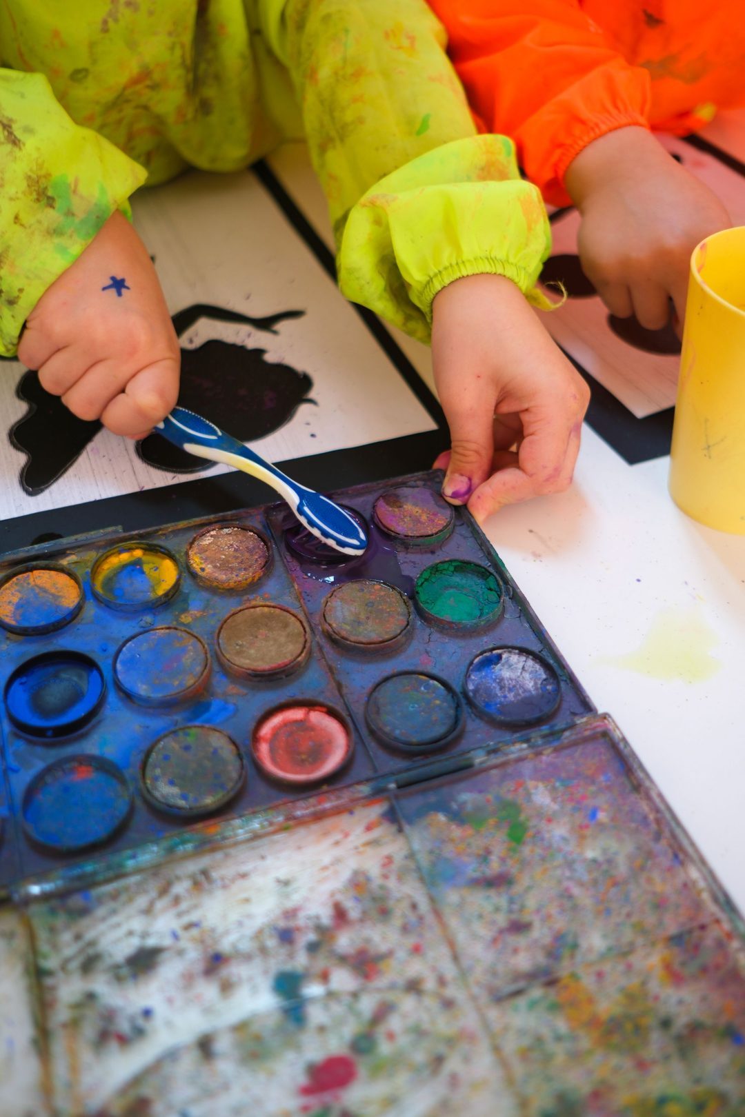 Mains d’enfants peignant avec une palette d’aquarelle
