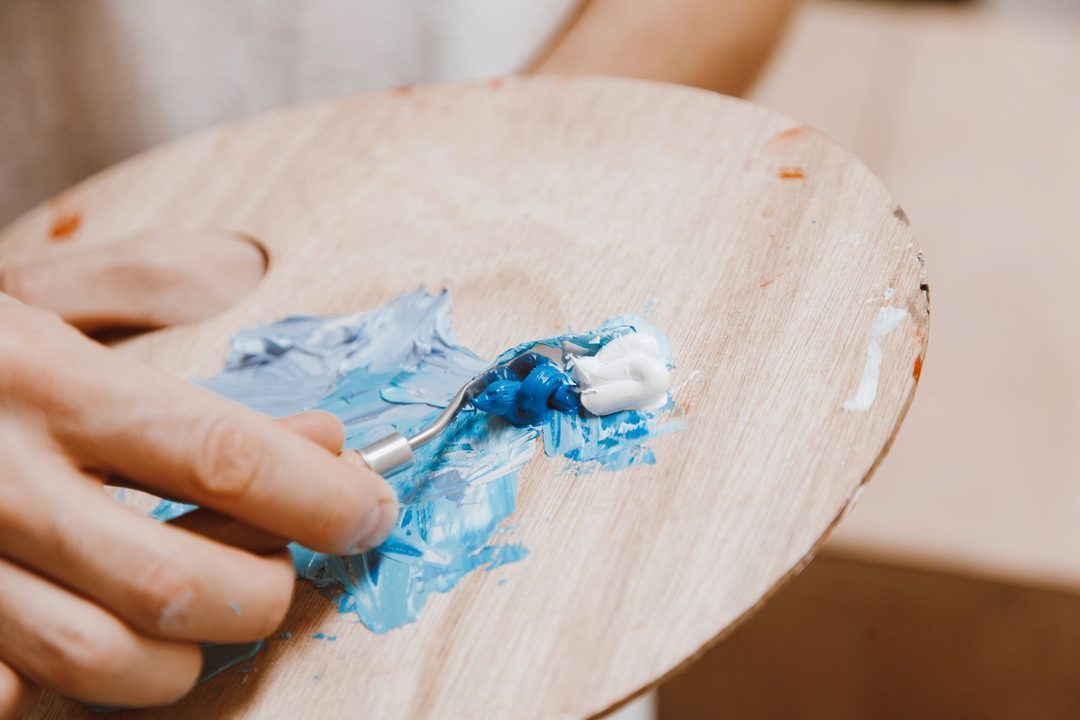 Main d’artiste mélangeant des teintes bleues et blanches sur une palette